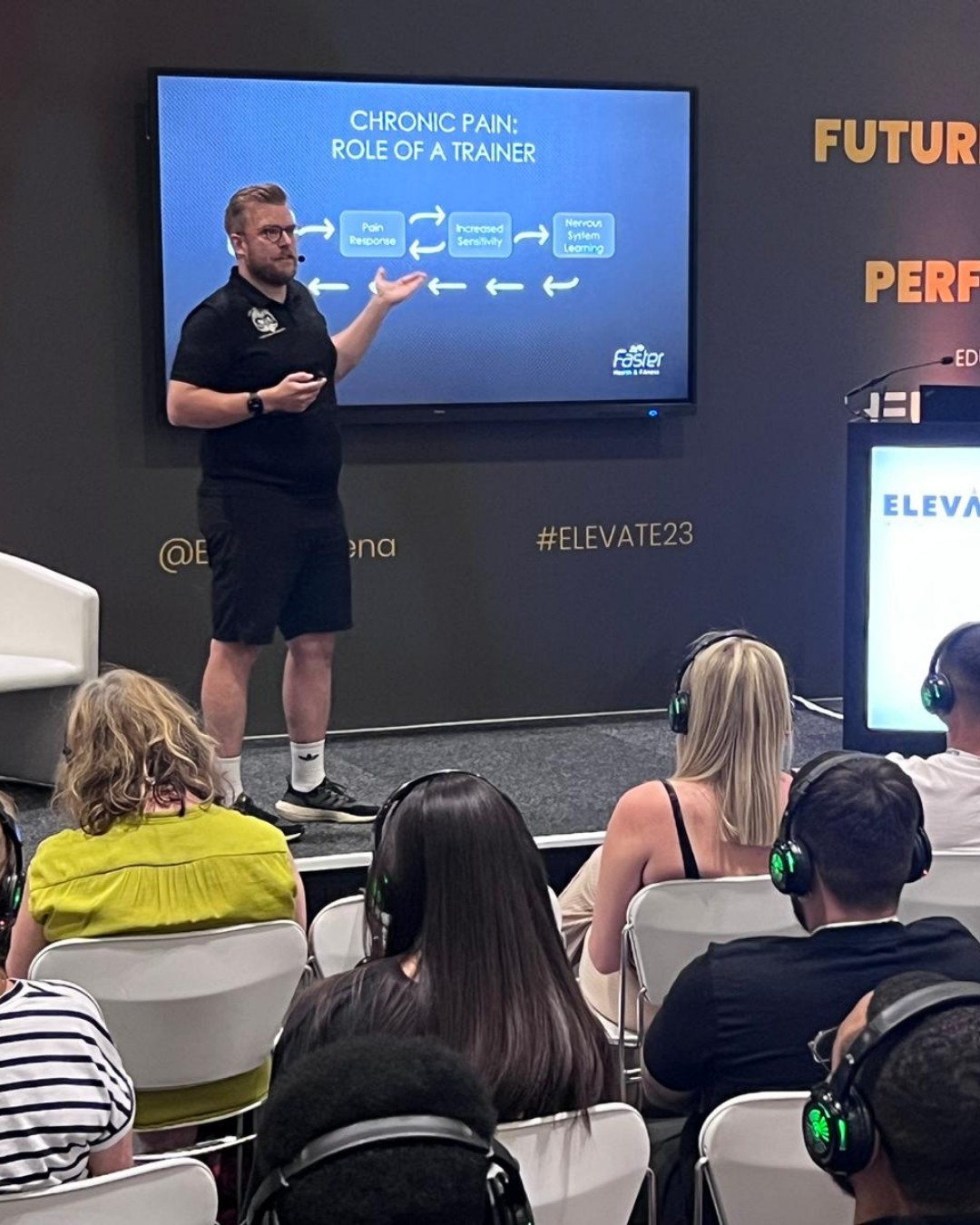 Ollie presenting on a conference stage to a room of trainers